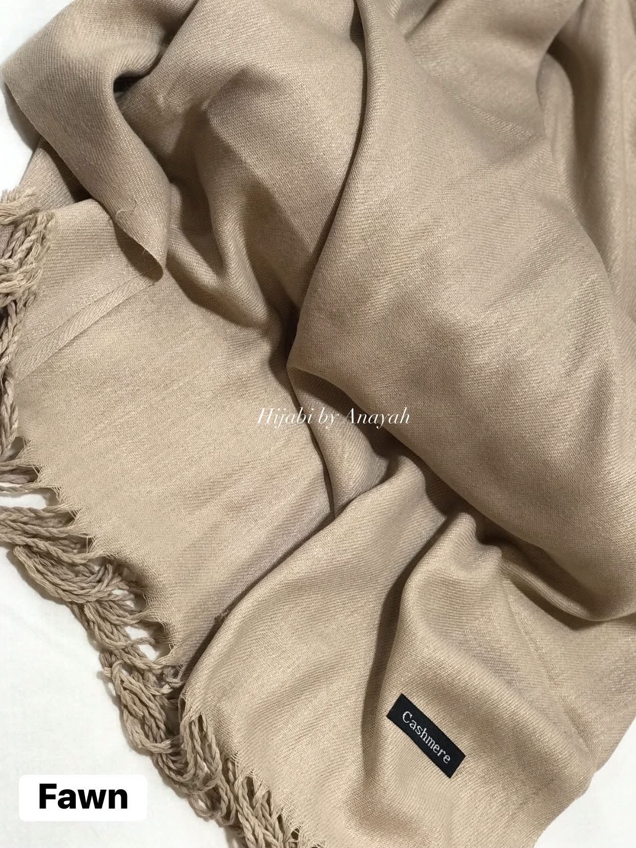 Beige scarf with fringes and a brand label on a white background