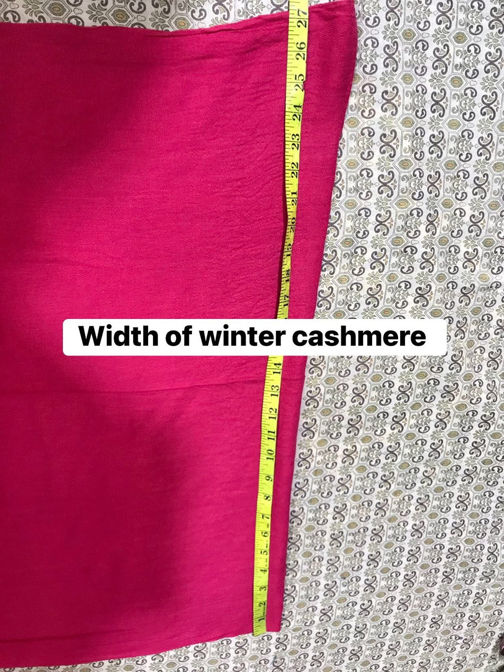 Pink fabric with a measuring tape showing its width on a patterned background
