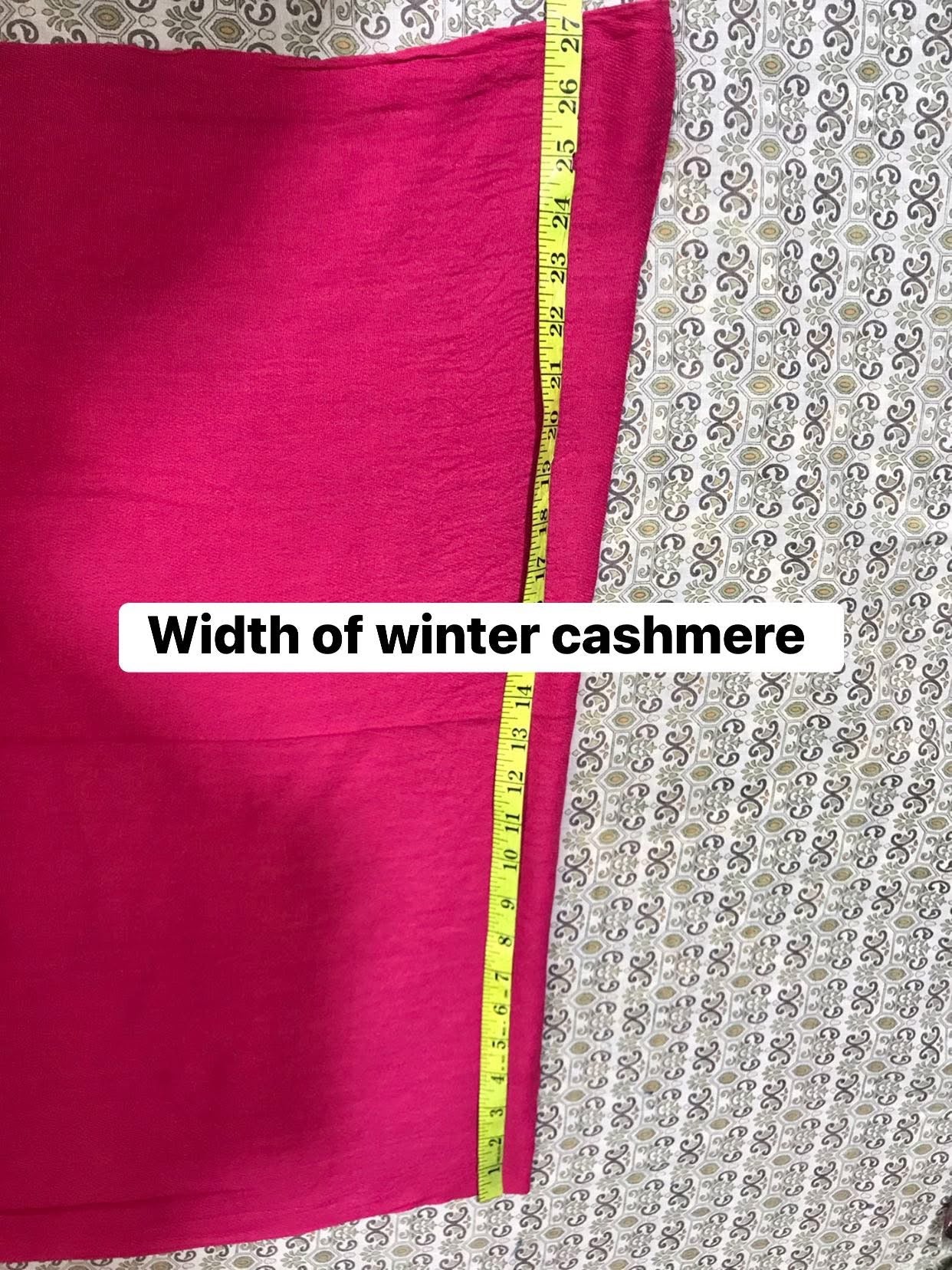 Pink fabric with a measuring tape showing its width on a patterned background