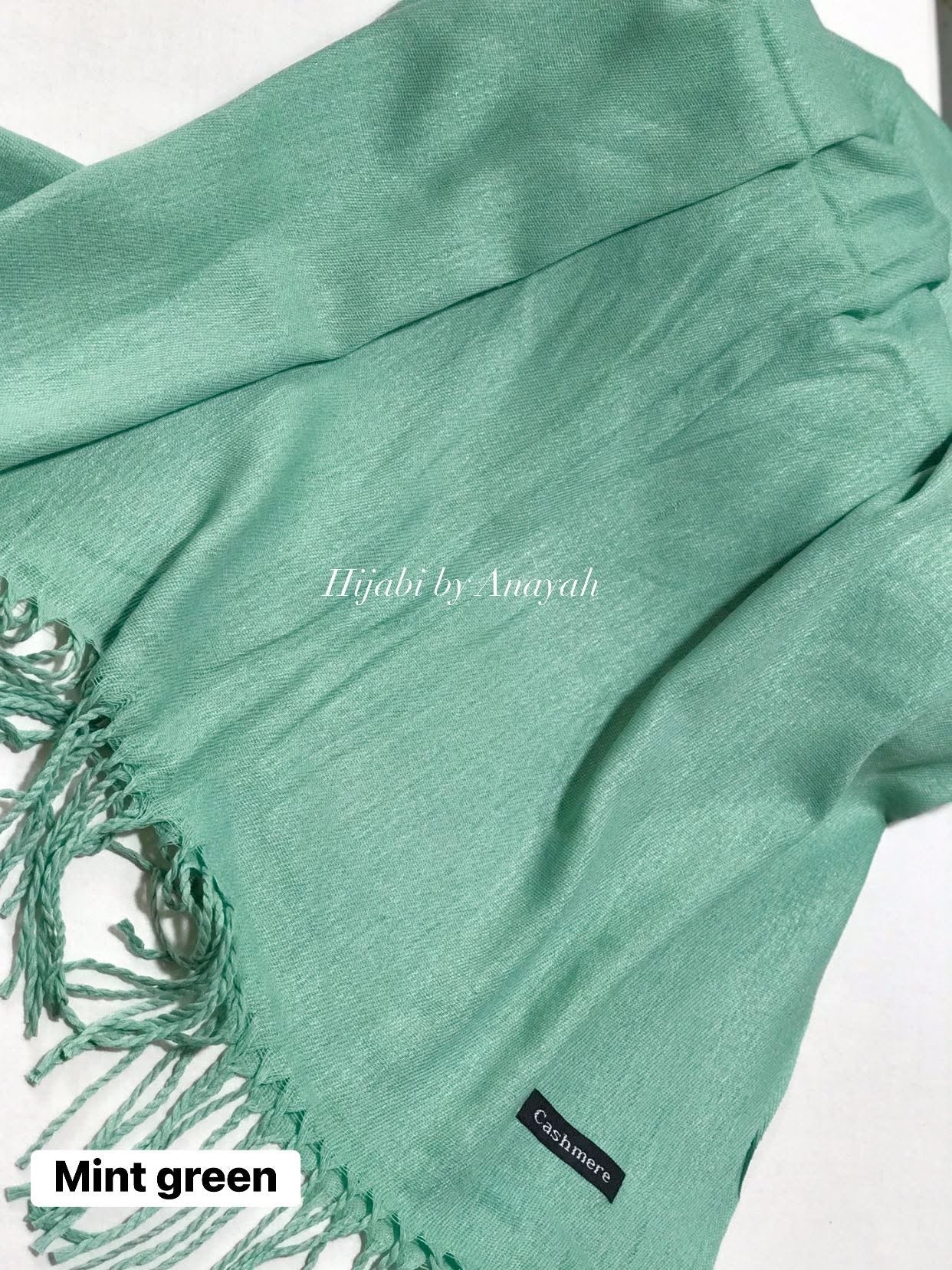 Mint green hijab with tassels on a white background