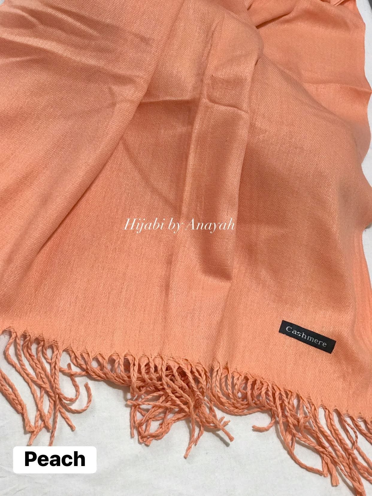 Peach hijab with fringes and 'Hijabi by Anayah' branding on a white background